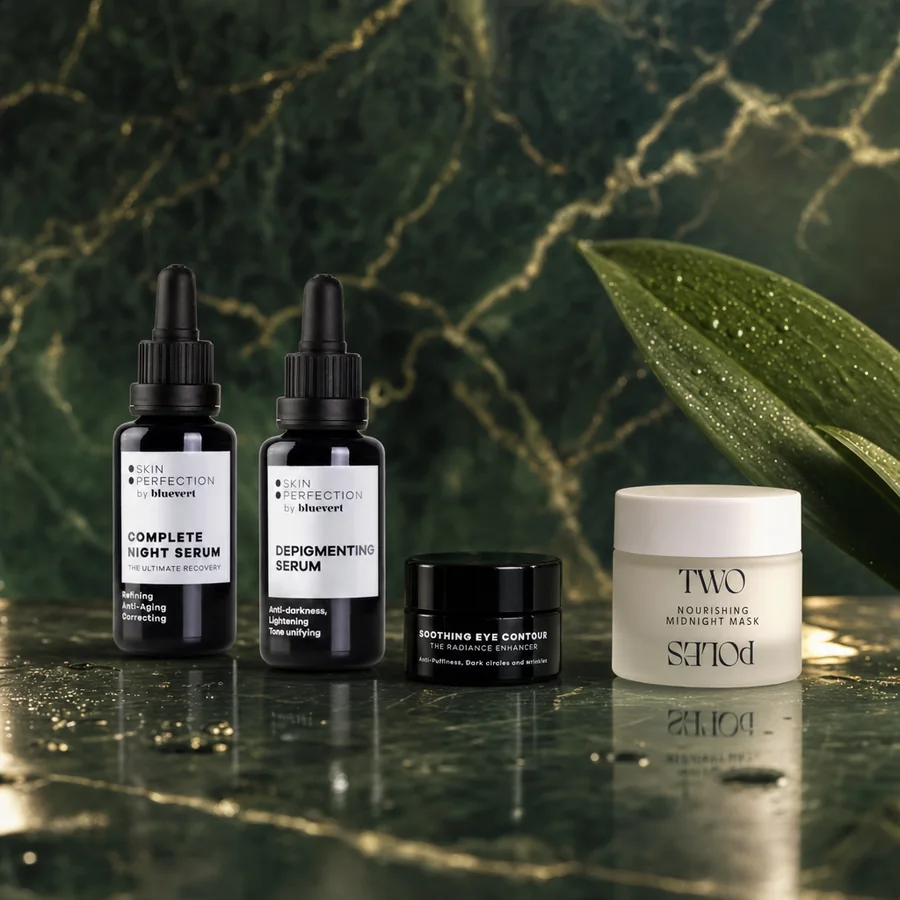 Dos sérums con cuentagotas, un contorno de ojos y una mascarilla de noche (Bluevert y Twopoles) sobre mármol verde oscuro, con una hoja grande detrás
