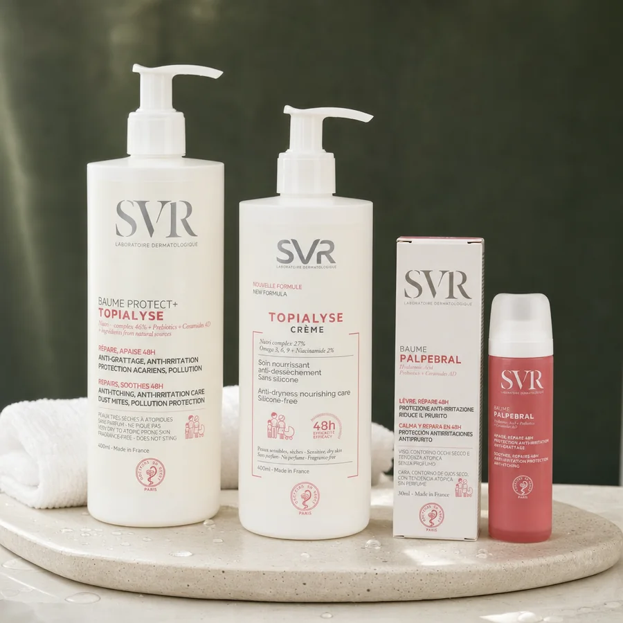Tres productos SVR Topialyse (Baume Protect+, Crème y Baume Palpebral) sobre una bandeja de piedra clara, con una toalla blanca detrás
